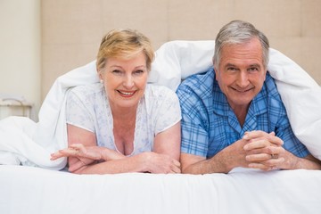 Fototapeta na wymiar Senior couple smiling under the duvet