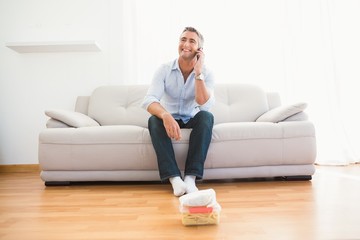 Smiling man phoning on the couch