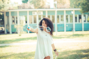 young beautiful moroccan curly woman blowing bubbles
