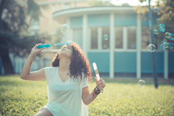 young beautiful moroccan curly woman blowing bubbles