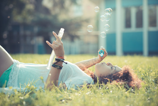 young beautiful moroccan curly woman blowing bubbles