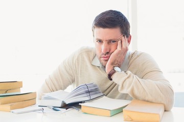Naklejka premium Bored casual businessman studying at his desk