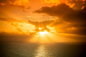 Dramatic sunset rays through a cloudy dark sky over the ocean