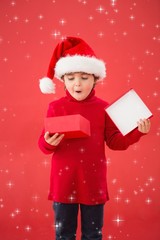 Composite image of festive little boy opening a gift