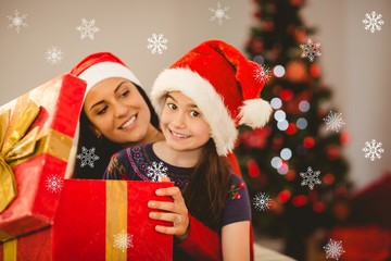 Fototapeta na wymiar Festive mother and daughter opening a christmas gift