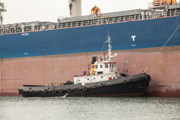 tug boat assisting huge ship in port