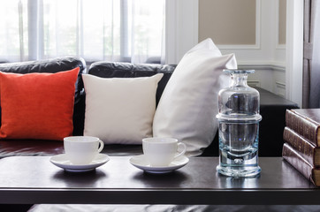 glass of water and white tea cups on wooden table