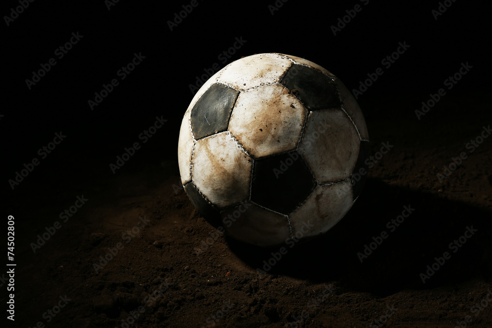 Poster Soccer ball on ground on dark background