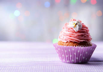Delicious birthday cupcake on table on light background