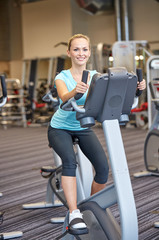 Fototapeta na wymiar smiling woman exercising on exercise bike in gym