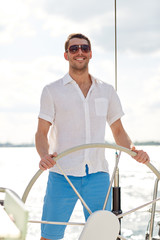 young man in sunglasses steering wheel on yacht