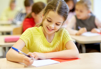 group of school kids writing test in classroom