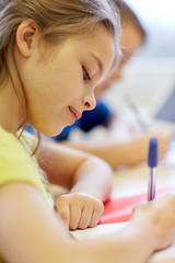 close up of school kids writing test in classroom