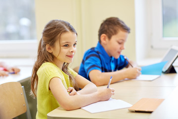 group of school kids writing test in classroom