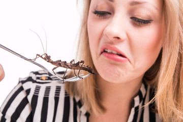 Disgusted woman eating insects with a fork in a restaurant