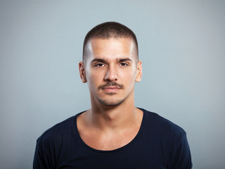 Portrait of a serious young man against gray background