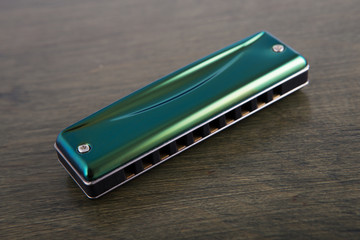 green harmonica on wooden board