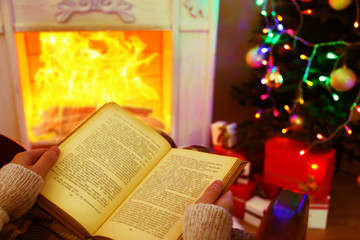 Woman holding book in front of fireplace