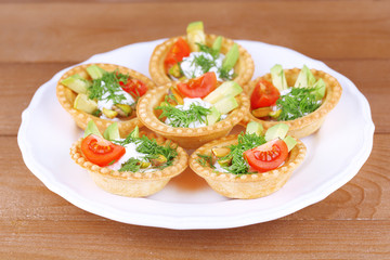 Tartlets with greens and vegetables with sauce on plate on