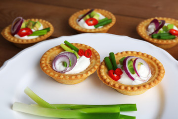 Tartlets with greens and vegetables with sauce on plate on