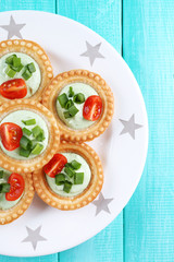 Tartlets with greens and vegetables with sauce on plate on