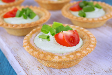 Tartlets with greens and vegetables with sauce on table
