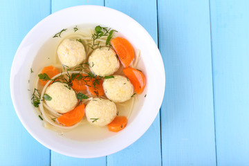 Soup with meatballs and noodles in bowl on wooden background