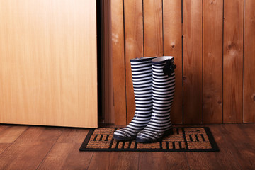 Dirty wellington boots on door mat in room