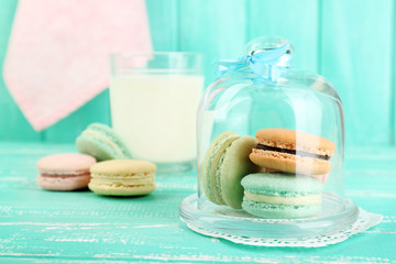 Gentle colorful macaroons in glass bell jar, milk glass and