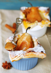 Small pear pies in cups, on wooden table