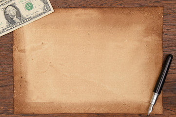 one dollar bill and pen with old papers for background.