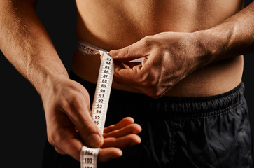 Unrecognizable man measuring waist