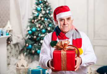 Obraz na płótnie Canvas Senior man holding a red gift box on Christmas background
