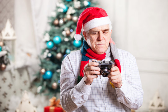 Senior man in Santa hat looking at display of retro style camera
