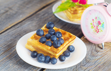 Belgian waffles with blueberries on the wooden rustic surface © iskra77