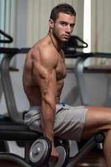 Fototapeta na wymiar Male Athlete Doing Heavy Weight Exercise For Biceps