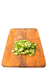 Chopped green chili peppers on wooden cutting board 