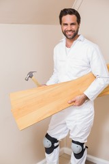 Carpenter holding planks and hammer