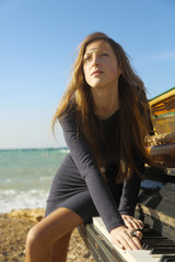 beautiful girl with notes from an old piano on the beach
