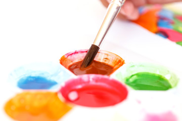 Close up hand holding brush with water paint tray