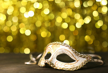Beautiful carnival mask on table on golden background