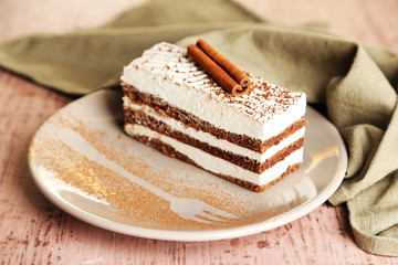 Tasty tiramisu cake on plate, on wooden table