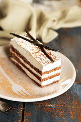 Tasty tiramisu cake on plate, on wooden table