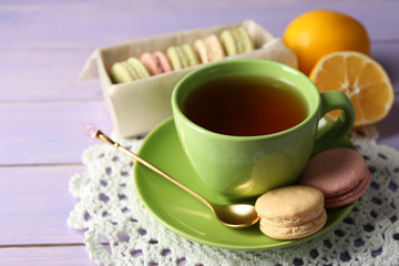 Fototapeta na wymiar Colorful macaroons with cup of tea on wooden background