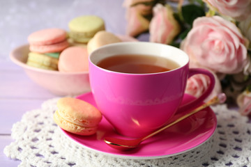 Obraz na płótnie Canvas Colorful macaroons with cup of tea on wooden background