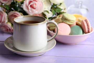 Obraz na płótnie Canvas Cup of tea with colorful macaroons on color wooden background