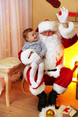 Obraz premium Santa Claus holding little cute girl near fireplace and