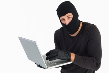 Burglar standing holding laptop while looking at camera