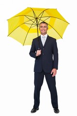Smiling businessman under yellow umbrella