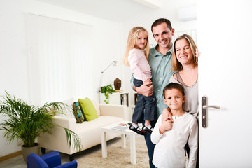 happy family with young kids welcoming a guests at home doorh